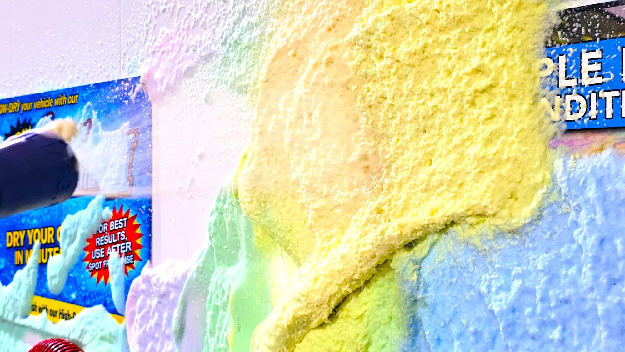 Colorful triple foam covering the wall and brush area inside a Badger self-serve bay