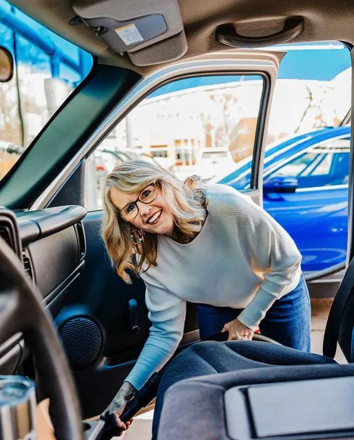 Woman vacuuming the floor of a vehicle